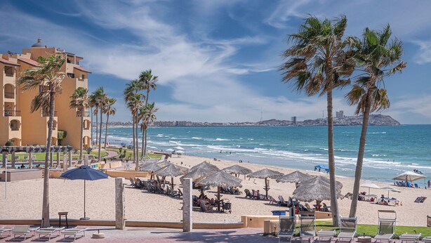 A beach resort with palm trees, sun loungers, and umbrellas. - Ocean View 2BR Condo at Princesa de Peñasco – Beautiful Balcony view C403 (Puerto Peñasco)