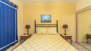 A bedroom with a bed, two bedside tables, a painting on the wall, and a blue curtain. - Ocean View 2BR Condo at Princesa de Peñasco – Beautiful Balcony view C403 (Puerto Peñasco)