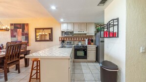 A kitchen with white cabinets, a microwave, a stove, a sink, and a trash can. - Ocean View 2BR Condo at Princesa de Peñasco – Beautiful Balcony view C403 (Puerto Peñasco)