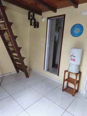 A room with a wooden staircase, a water dispenser, a door, and a wall with a decorative plate. - Cozy Chalet, Your Beach Retreat (Cabo de Santo Agostinho)