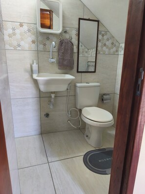 Une salle de bain équipée d’un lavabo, de toilettes, d’un miroir et d’un porte-serviettes.