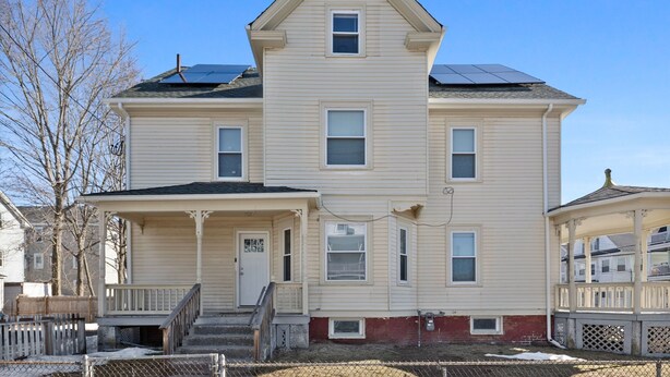 A two-story house with a front porch, a small attached garage, and solar panels on the roof. - Charming 2-bedroom apartment in charming Attleboro (Attleboro)