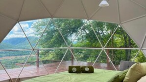 Une pièce en forme de dôme géodésique, équipée d’un lit, d’oreillers et de luminaires suspendus.