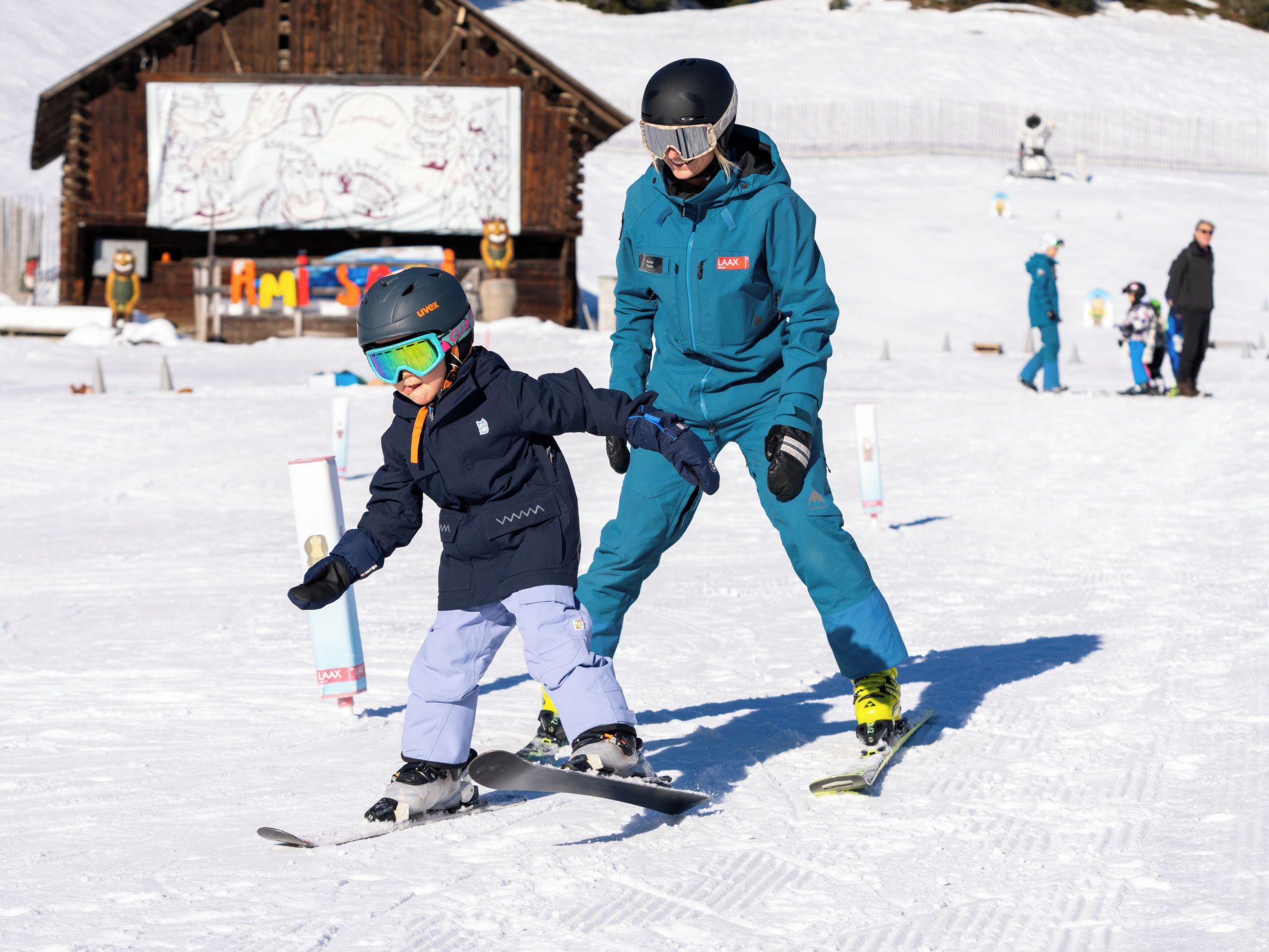 A snowy ski slope with a wooden building in the background.