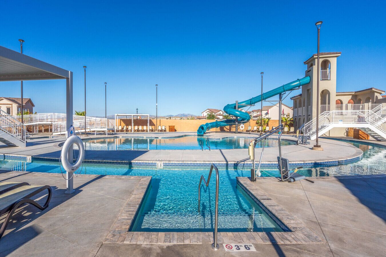 Une piscine avec un toboggan, une bouée de sauvetage et un panneau indiquant qu’il est interdit de plonger.