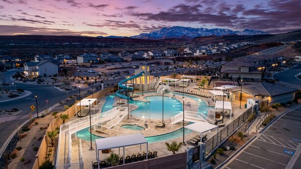 A resort with a large swimming pool, a water slide, and a view of mountains.