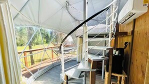 Telttaa muistuttava rakennelma, jossa on metallinen portaikko ja ulkona puinen terassi.
