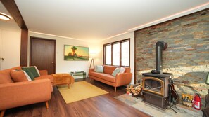 Ein Wohnzimmer mit einer Couch, einem kleinen Tisch, einem Gemälde, einem Kamin und einer Steinwand.