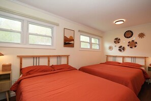 Una habitación con dos camas, un ventanal y decoración en las paredes.