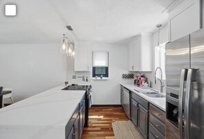 A modern kitchen with a central island, stainless steel appliances, and a view of the outdoors.