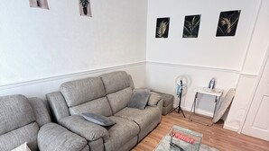 Ein modernes Wohnzimmer mit einem grauen Ecksofa, einem Glastisch und einem flauschigen Teppich in Grau.