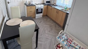 Eine kleine Küche mit Mikrowelle, Herd und Holzschränken.