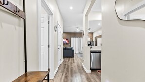 A modern interior with a wooden bench, a kitchen with a dishwasher, and a grey sofa in the background. - 4BR Disney Area Home and Resort, Themed Rooms, Arcade Games, Gym and Pool. (Davenport)
