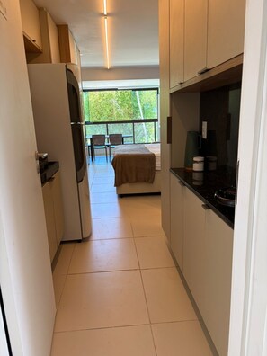 Ein schmales Entree mit Küchenzeile, einem Esstisch mit Stühlen und einem Bett mit Blick.