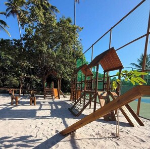 Ein Sandspielplatz mit hölzernen Klettergerüsten und einem eingezäunten Bereich.