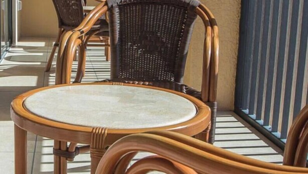 A wicker chair with a round table, a woven chair, and a metal railing. - Spacious 1BR Deluxe Villa w/ Full Kitchen, Balcony & Jetted Tub - 800 Sq Ft (Orlando)