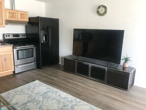 Eine Küche mit Kühlschrank, Backofen und einem Flachbildfernseher auf einem Lowboard.