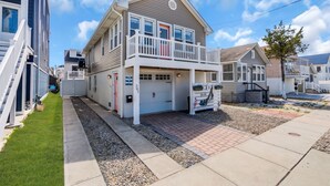 A two-story house with a front porch, a garage, and a small front yard. - Game Room | 3 Blocks 2 Beach | Linens + Towels (Seaside Heights)
