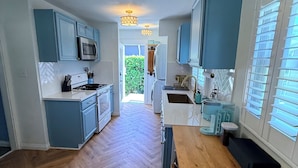 A modern kitchen with a herringbone wood floor, light blue cabinets, and a central island. - 0.5 Mile Walk To Sofi - Art Deco Beach Cottage - Entire Home (Inglewood)