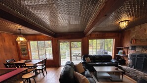 Een knus interieur met een houten plafond, een open haard, een bank en een zithoek.