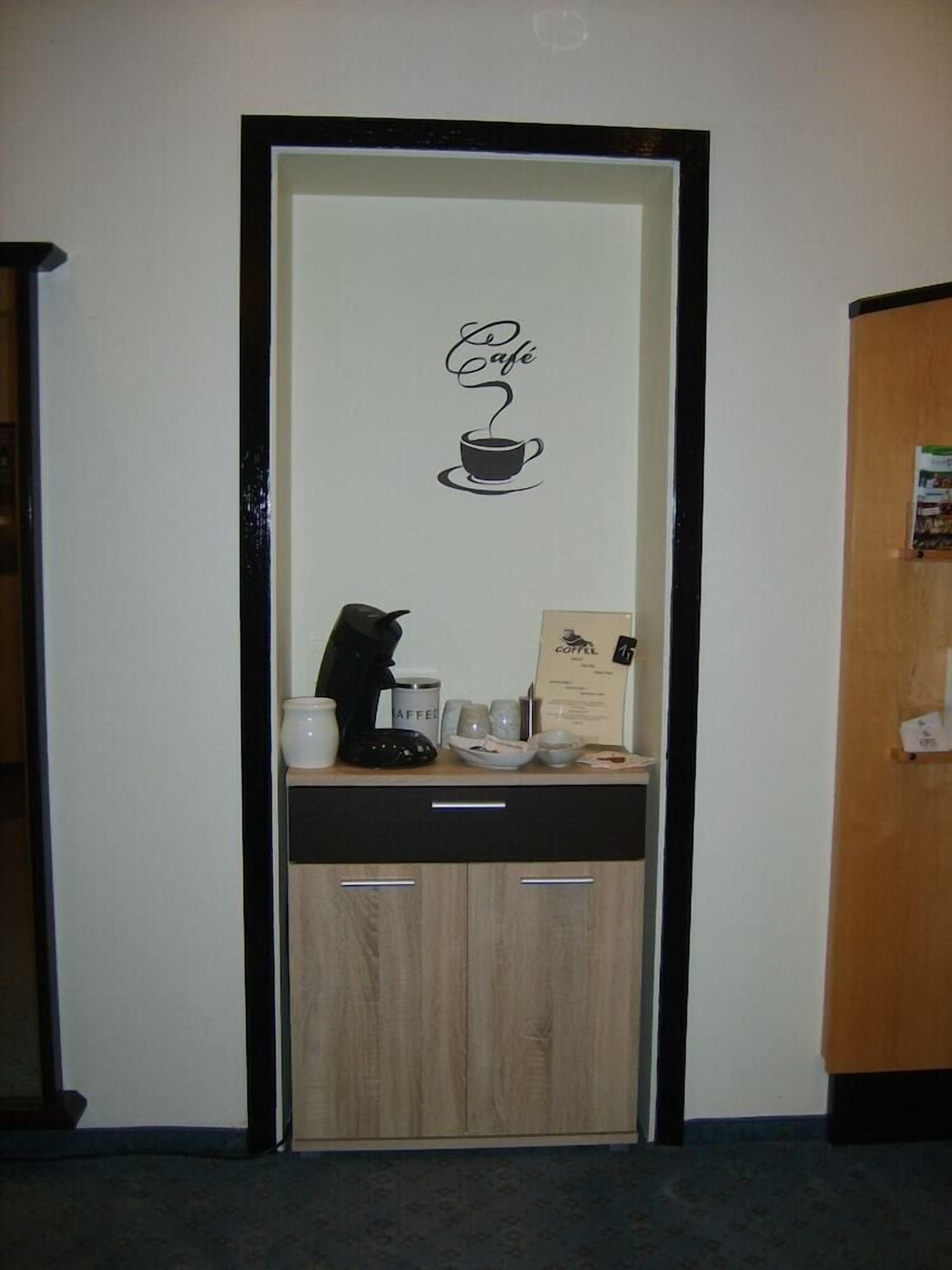 Een deur met een bord met koffie-thema, een koffieapparaat en een koffiekop op een toonbank.