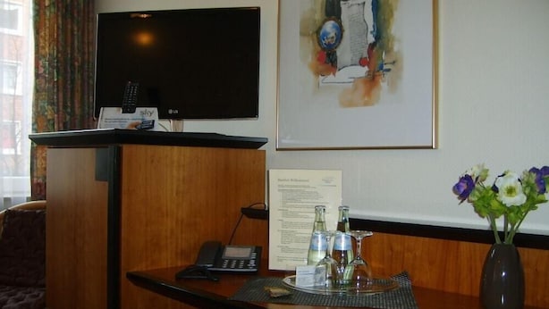 A hotel reception desk with a flat-screen TV, a telephone, and a framed artwork on the wall. - City Hotel Deutsches Haus (Hagen)