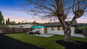 A residential backyard with a lawn, patio furniture, and a tree. - King Bed, Garage, Gated Backyard, 4BR/2Bth (El Cajon)