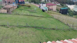 A rural landscape with houses, a fenced field, and a body of water in the distance. - Altico Lola Martínez (Tota)