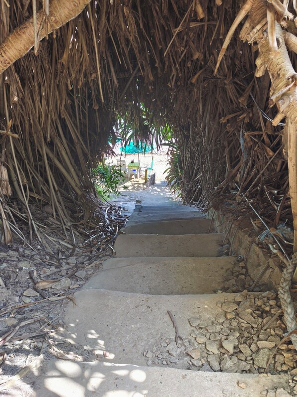 A pathway leading through a structure made of natural materials, with steps ascending towards a distant view. - Cozy chalet, your beach retreat. (Cabo de Santo Agostinho)