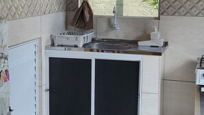 A compact kitchen with a built-in stove, a sink, and a small cabinet.