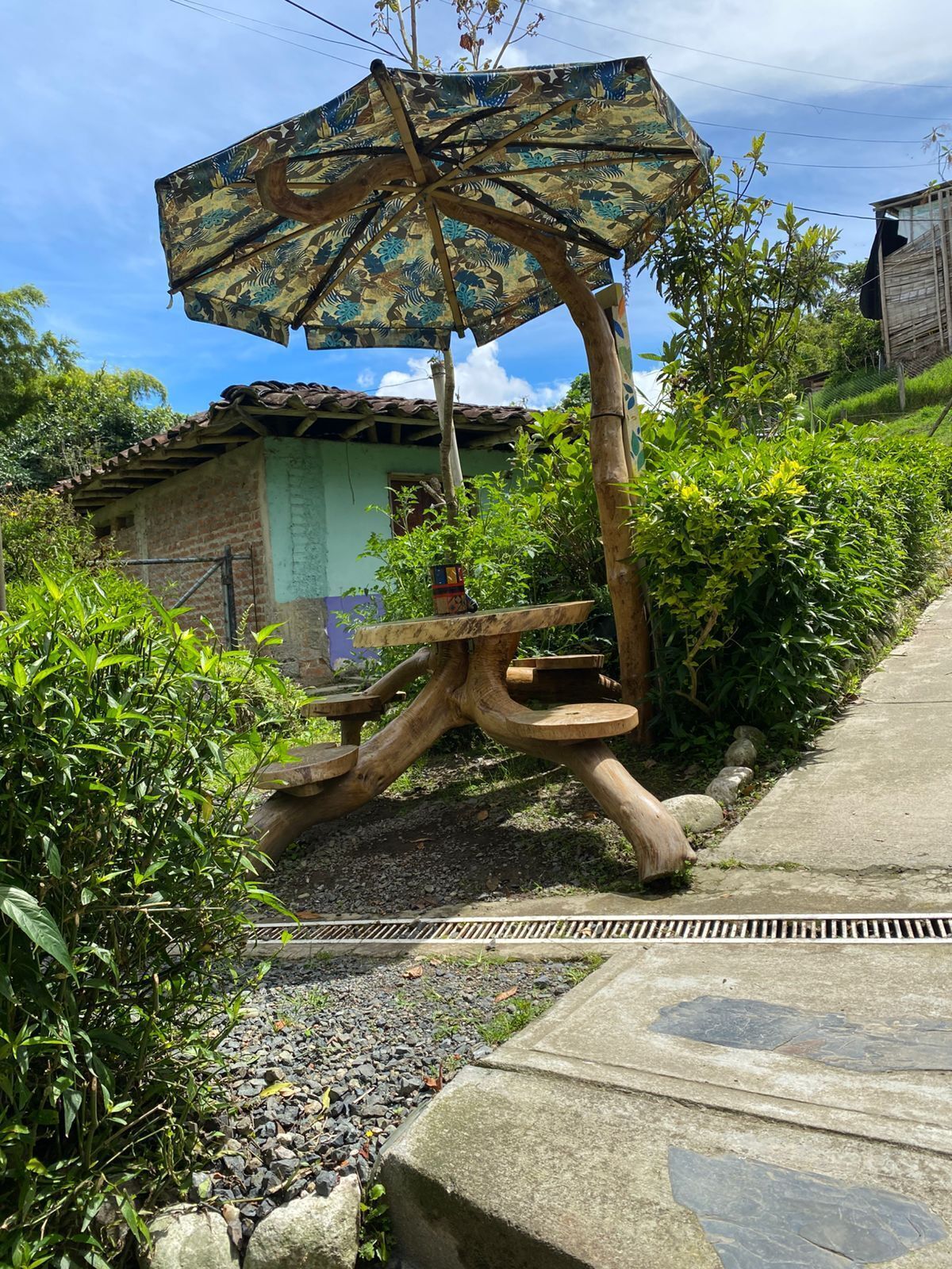 A garden with a wooden sculpture, a concrete pathway, and a building with a tiled roof.