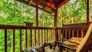 Eine Holzterrasse mit Sitzgelegenheiten, umgeben von einem Wald.