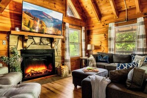A log cabin interior with a fireplace, a television, and a couch. - Hot Tub, Arcade, Sauna, Dog Run, 3 Kg Beds, Slp 12 (Pigeon Forge)