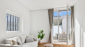 Ein modernes Wohnzimmer mit einer Couch, einem kleinen runden Tisch und einer Topfpflanze.