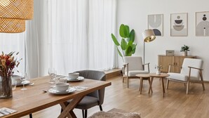 Ein modernes Wohnzimmer mit Essbereich, großen Fenstern und einer Pflanze.