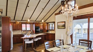 A kitchen with wooden cabinets, a central island, and a dining area with a table set for six.