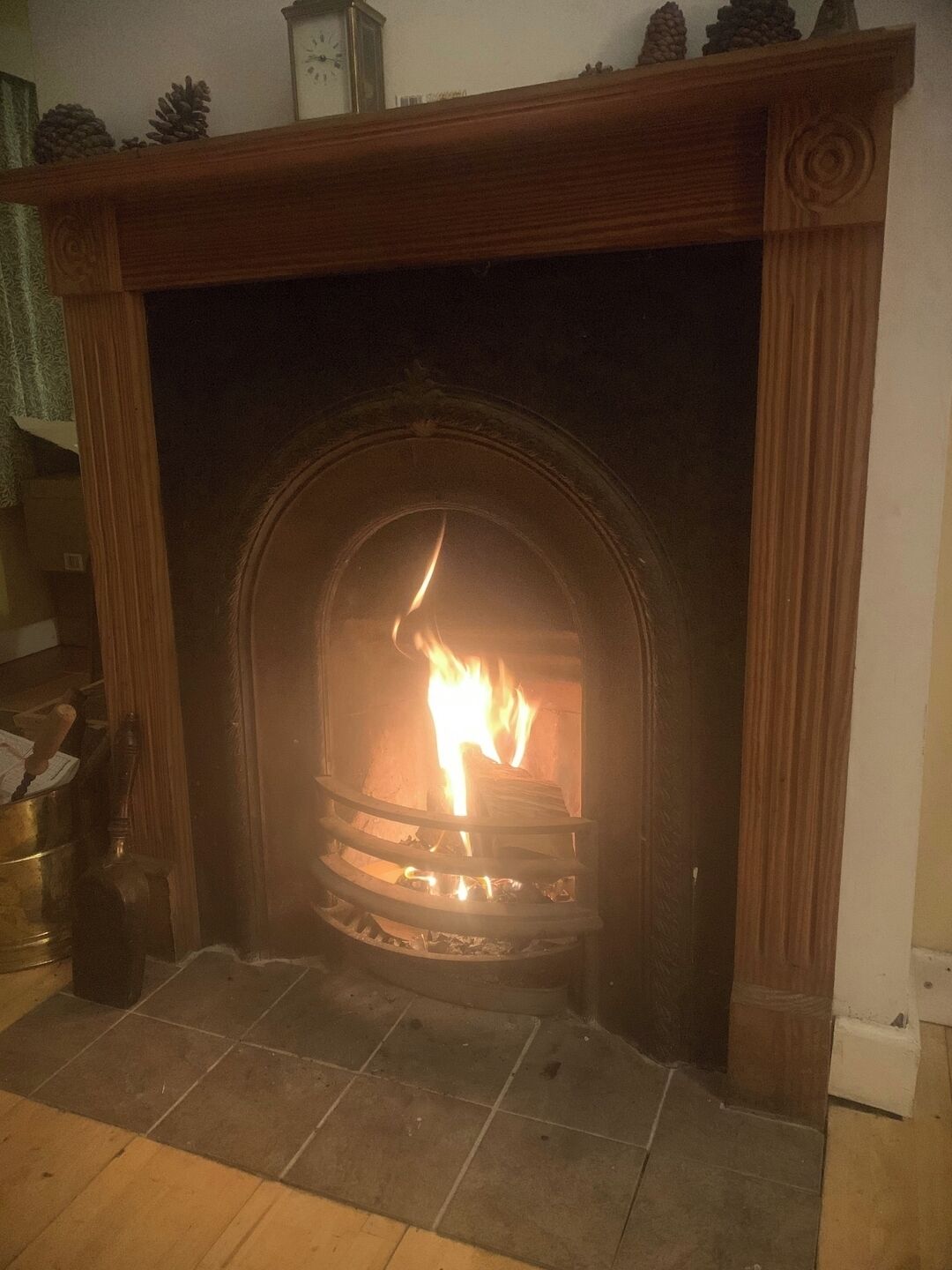 A fireplace with a fire burning inside, surrounded by a wooden mantel and a stone hearth.