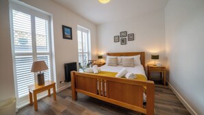 Une chambre à coucher avec un lit en bois, deux tables de chevet, un radiateur et un luminaire fixé au plafond.