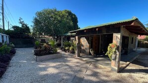 A building with a gravel driveway, a covered entrance, and potted plants. - Private 3BR Pool Home Near Tamarindo & Playa Conchal (Tempate)