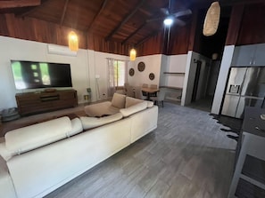 Ein Wohnzimmer mit einer Couch, einem Fernseher und einem Essbereich mit Stühlen und einem Tisch.