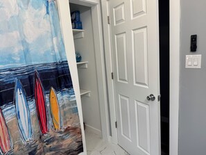 Ein Zimmer mit einer weißen Tür, einem Regal mit Kisten und einem Bild von Surfbrettern an der Wand.