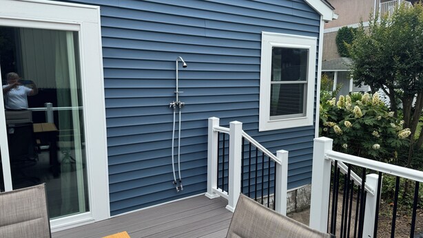 A blue house with a deck, a sliding glass door, a small window, and a white railing. - Downtown Rehoboth Ave Renovated Condo Pet Friendly (Rehoboth Beach)