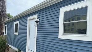 A residential building with a blue siding exterior, a white door, and a large window. - Downtown Rehoboth Ave Renovated Condo Pet Friendly (Rehoboth Beach)