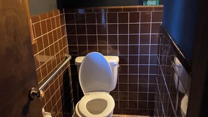 Une salle de bain avec des toilettes, une étagère contenant des articles de toilette et des carreaux de sol à motifs.