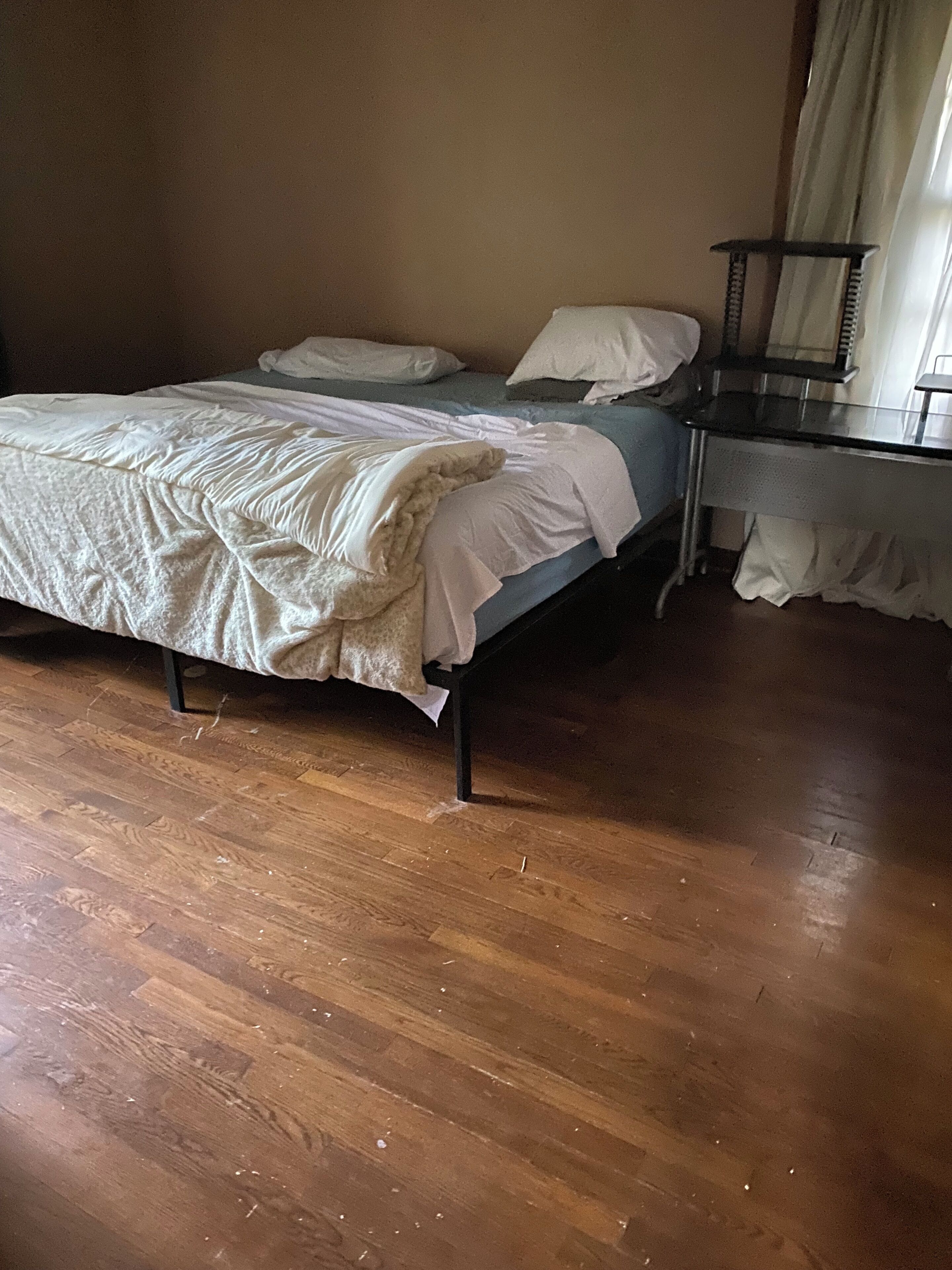 Une chambre à coucher avec un lit, une table de chevet et une fenêtre avec des rideaux.