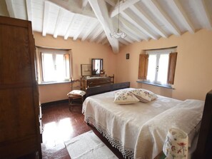 Una camera da letto con un letto, una cassettiera, una sedia e finestre.