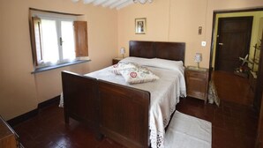 Ein Schlafzimmer mit einem hölzernen Bett, einem Fenster, einer Tür und einem Deckenventilator.