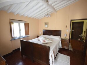 A bedroom with a wooden bed, a window, a door, and a ceiling fan. - Casa Irene by Interhome (Colognora)