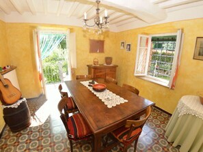 Zona pranzo con tavolo in legno, sedie, un lampadario e vista dalla finestra.