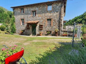 A stone building with a green door, windows, and potted plants. - Casa Irene by Interhome (Colognora)